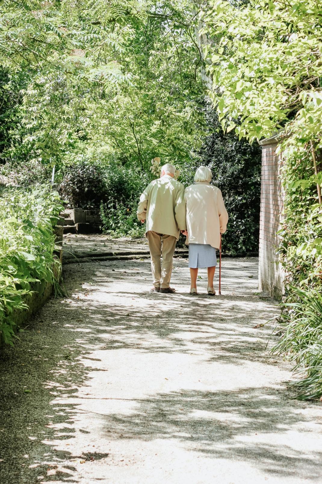 Twee oudere mensen wandelen in een park.