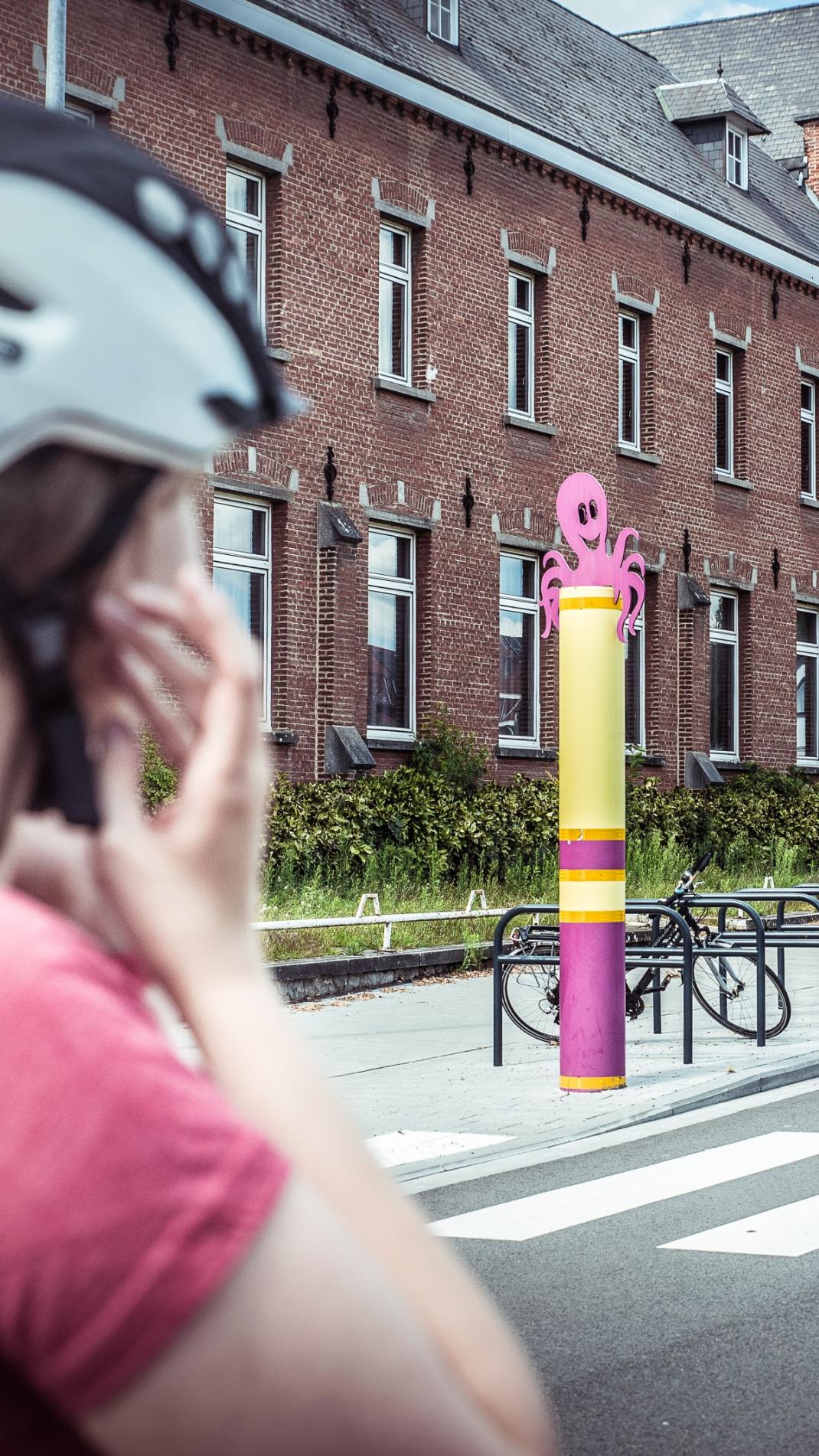 Fietser zet fietshelm op met oversteekplaats aan een school op de achtergrond.