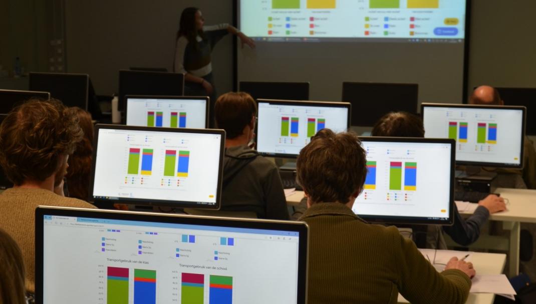 Klaslokaal met mensen die aan computerschermen grafieken bestuderen